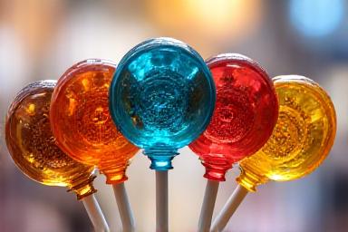 Colorful clockwork-themed lollipops with gear patterns inside translucent candy shells
